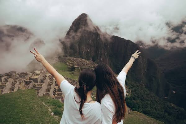 Two students holding their arms up to Machu Picchu