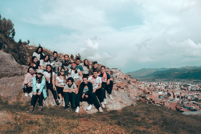 Group of students on hillside overlooking Cusco in mountainous landscape