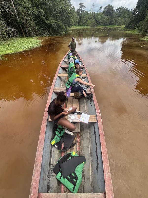 Enviornmental-science-Peru-Amazon-Iquitos-study Students on Environmental Science trip sitting and writing in a canoe